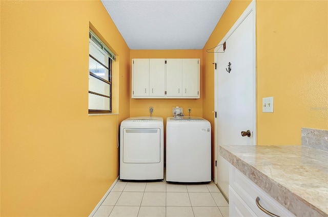 clothes washing area featuring baseboards, washing machine and dryer, light tile patterned floors, cabinet space, and a textured ceiling