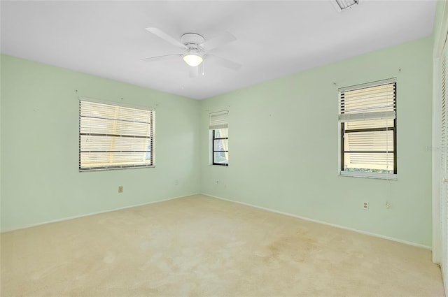 empty room with light colored carpet, baseboards, and ceiling fan