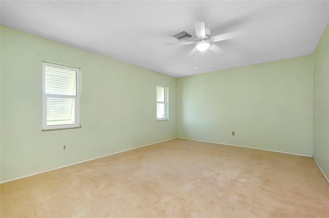 spare room featuring light carpet, baseboards, a textured ceiling, and a ceiling fan