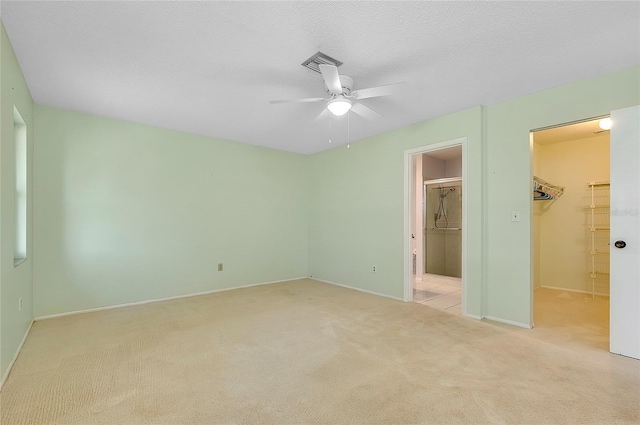 unfurnished bedroom featuring carpet, ensuite bath, a spacious closet, a closet, and a textured ceiling