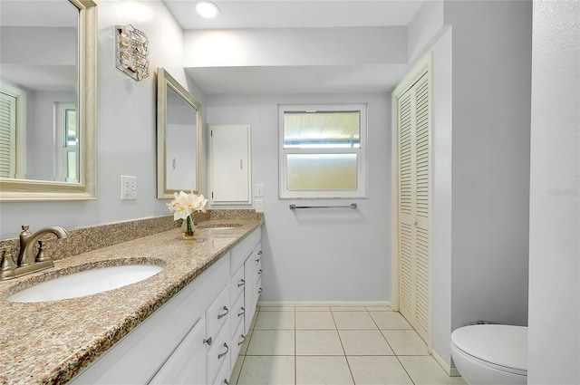 full bath featuring a sink, toilet, double vanity, and tile patterned flooring