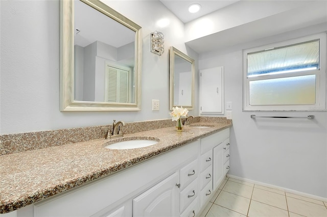 full bath with tile patterned flooring, double vanity, baseboards, and a sink