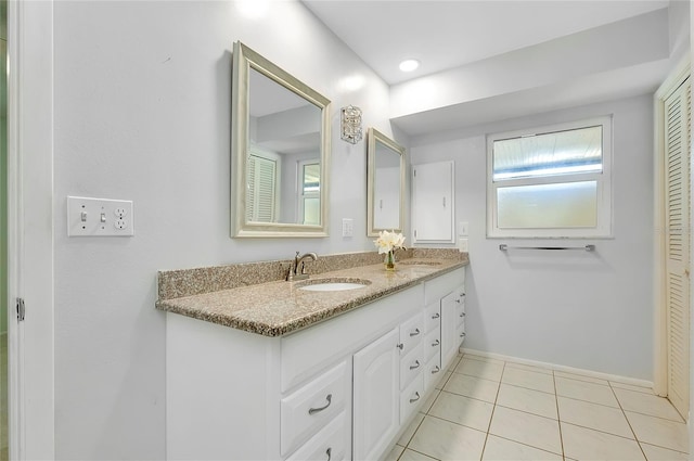 bathroom featuring tile patterned floors, double vanity, baseboards, and a sink