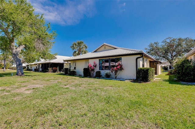 view of front of home featuring stucco siding, a front lawn, and a tile roof