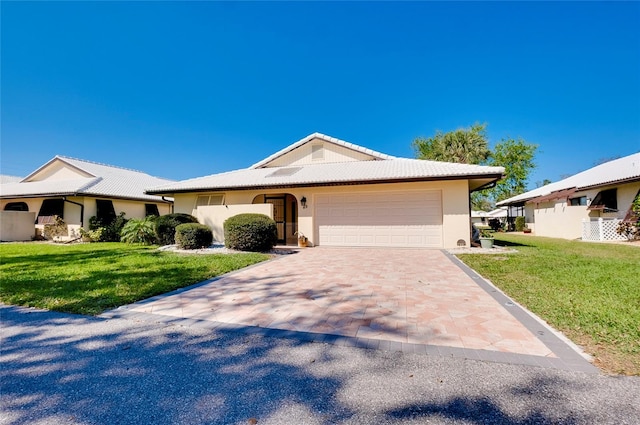 ranch-style home with a front lawn, decorative driveway, an attached garage, and stucco siding