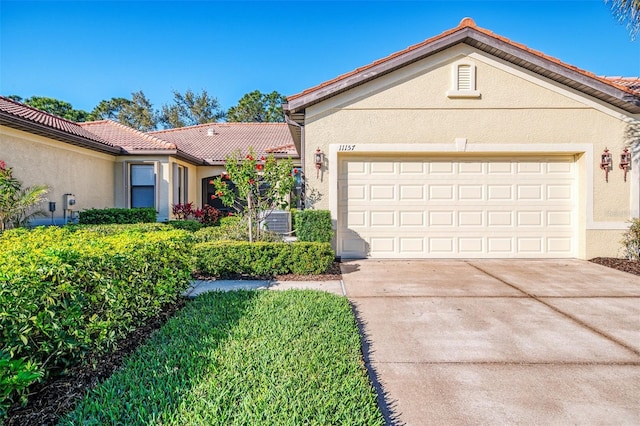 ranch-style house featuring stucco siding, a garage, driveway, and a tile roof