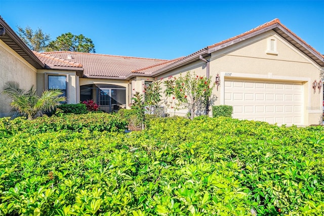 view of front of property with stucco siding, an attached garage, and a tiled roof