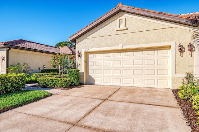 view of front of house featuring stucco siding, concrete driveway, a tile roof, and an attached garage