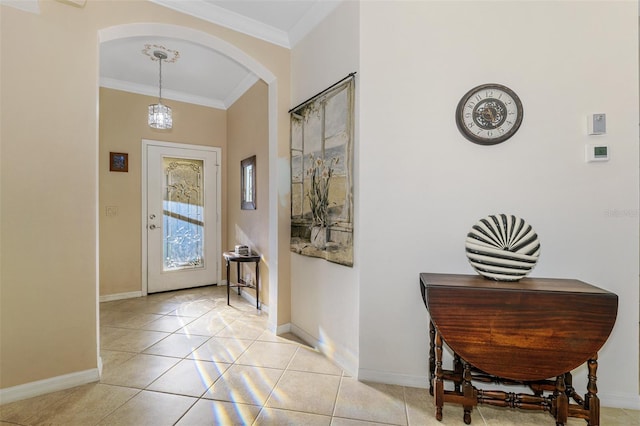 foyer featuring crown molding, light tile patterned flooring, baseboards, and arched walkways