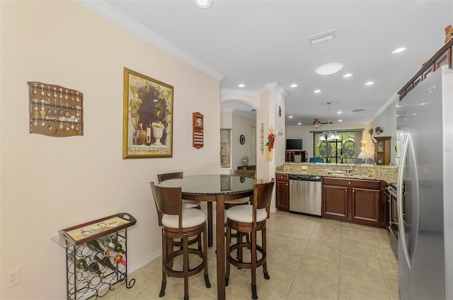 kitchen with light tile patterned floors, a peninsula, arched walkways, ornamental molding, and stainless steel appliances