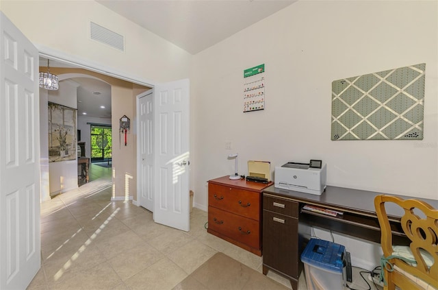 office area with light tile patterned floors, visible vents, arched walkways, and baseboards