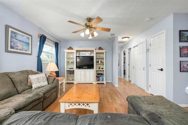 living room with visible vents, baseboards, wood finished floors, a textured ceiling, and a ceiling fan