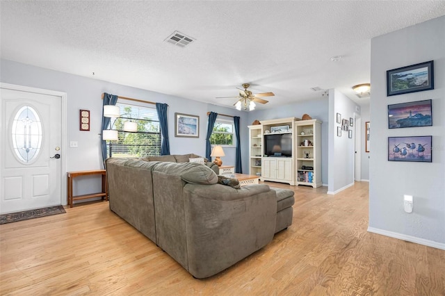 living room with visible vents, a ceiling fan, a textured ceiling, light wood finished floors, and baseboards