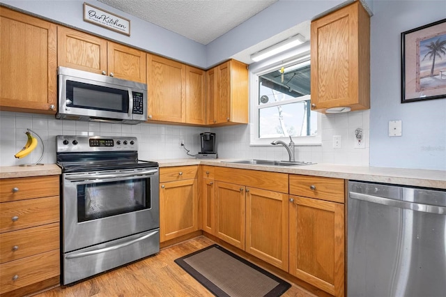 kitchen with light countertops, light wood-style floors, appliances with stainless steel finishes, and a sink