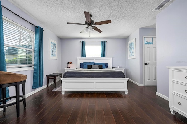 bedroom with visible vents, a textured ceiling, wood finished floors, baseboards, and ceiling fan