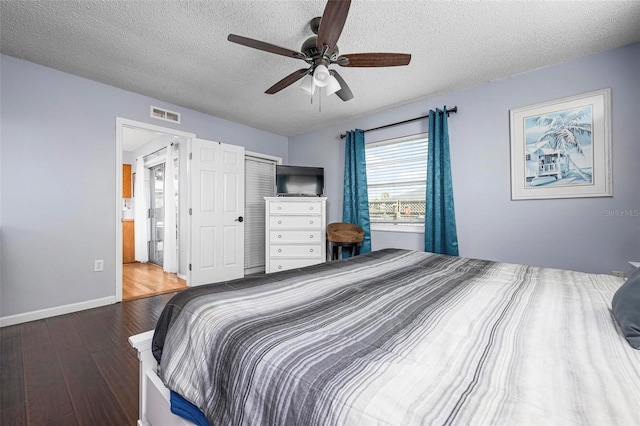 bedroom featuring wood finished floors, baseboards, visible vents, ensuite bath, and a textured ceiling