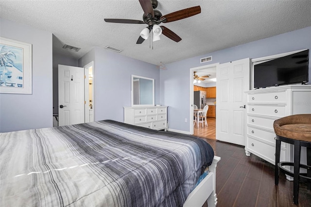 bedroom with visible vents, a textured ceiling, and dark wood finished floors