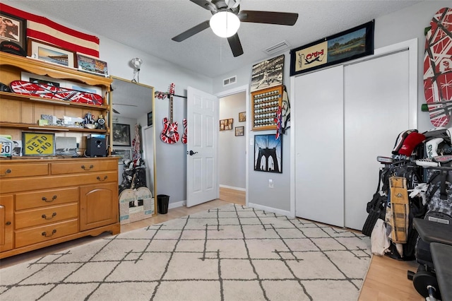 interior space featuring visible vents, a textured ceiling, light wood-style floors, and a ceiling fan