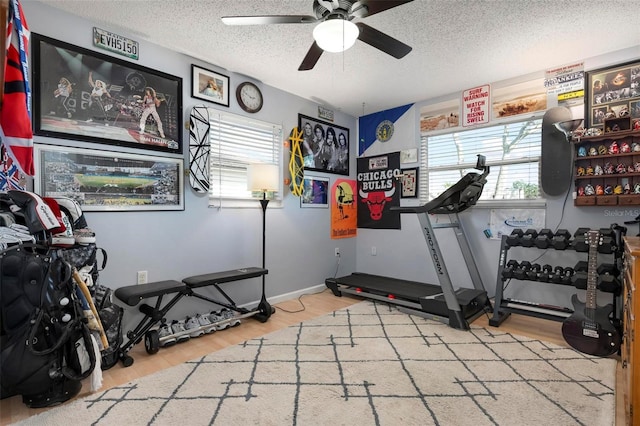 exercise room featuring ceiling fan, a textured ceiling, and wood finished floors