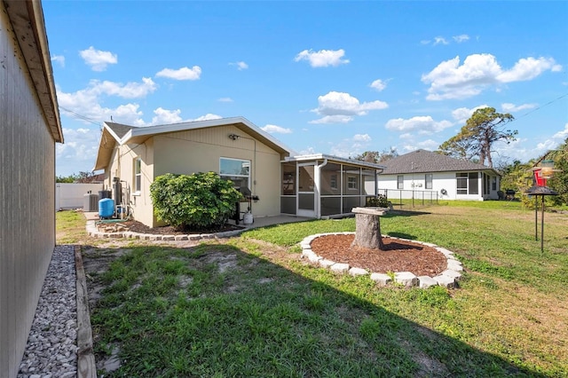 back of property with fence, a lawn, and a sunroom