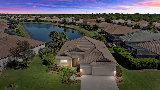 aerial view at dusk featuring a residential view and a water view