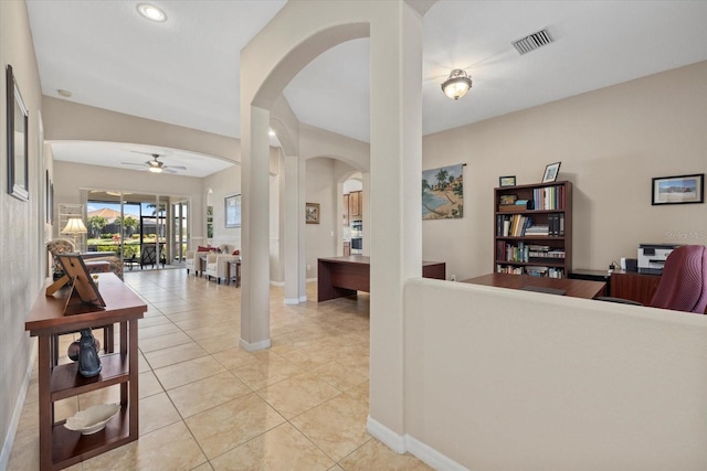 interior space featuring light tile patterned floors, arched walkways, visible vents, and ceiling fan