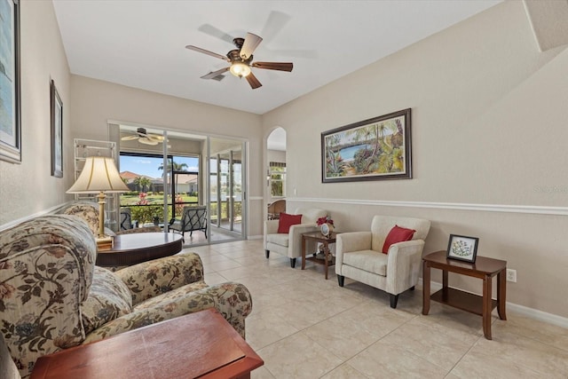 living room with baseboards, arched walkways, ceiling fan, and light tile patterned flooring