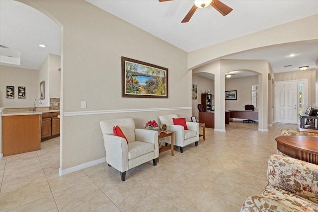 living room with light tile patterned floors, baseboards, arched walkways, and a ceiling fan