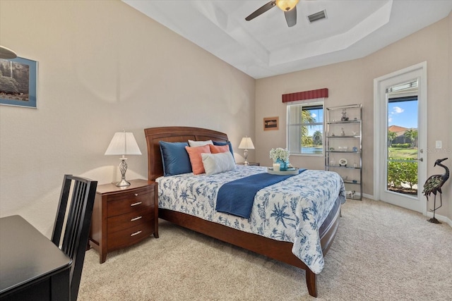 bedroom with visible vents, light carpet, a raised ceiling, a ceiling fan, and baseboards