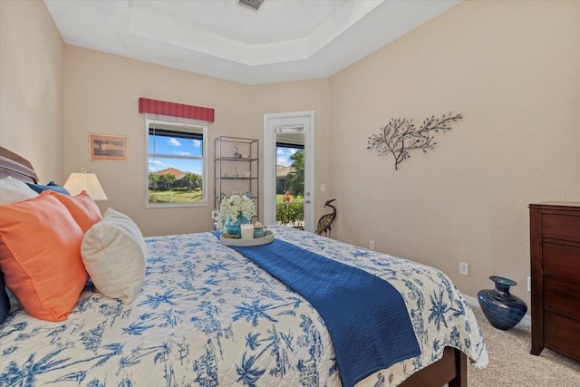 bedroom with access to exterior, visible vents, a tray ceiling, and carpet floors