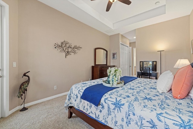 bedroom with a raised ceiling, a closet, carpet floors, baseboards, and ceiling fan