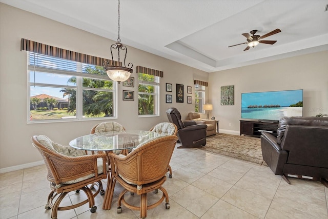 dining area with light tile patterned floors, baseboards, a raised ceiling, and a ceiling fan