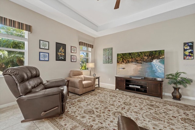 tiled living room with a wealth of natural light, a ceiling fan, and baseboards