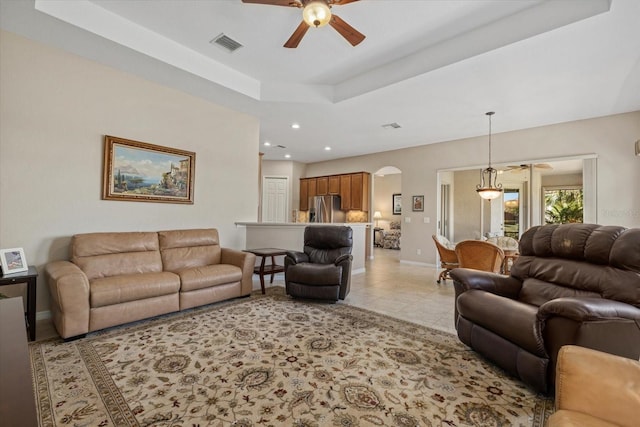 living room featuring visible vents, baseboards, light tile patterned floors, arched walkways, and a raised ceiling