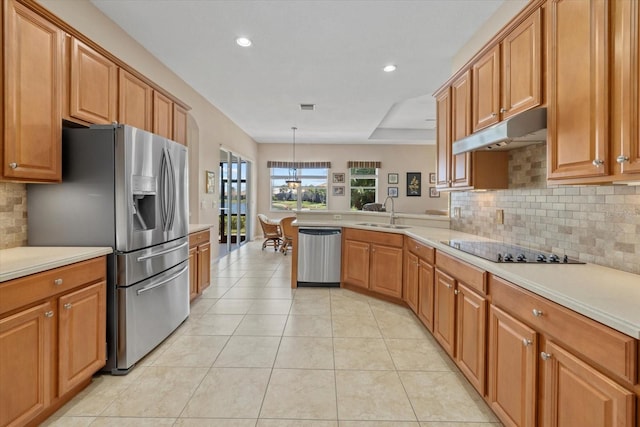 kitchen with a peninsula, a sink, stainless steel appliances, light countertops, and under cabinet range hood