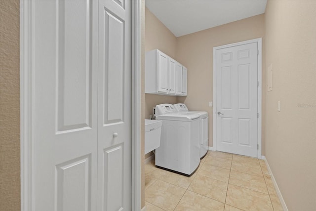 washroom with light tile patterned floors, independent washer and dryer, cabinet space, and baseboards