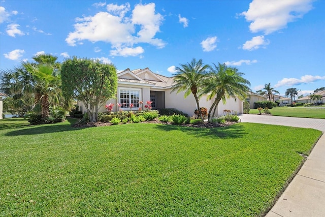 view of front of house featuring decorative driveway, a garage, a front yard, and stucco siding