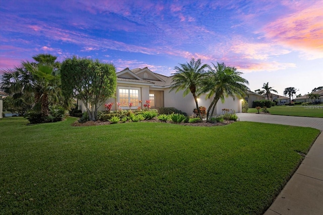 view of front of property with stucco siding, an attached garage, decorative driveway, and a yard