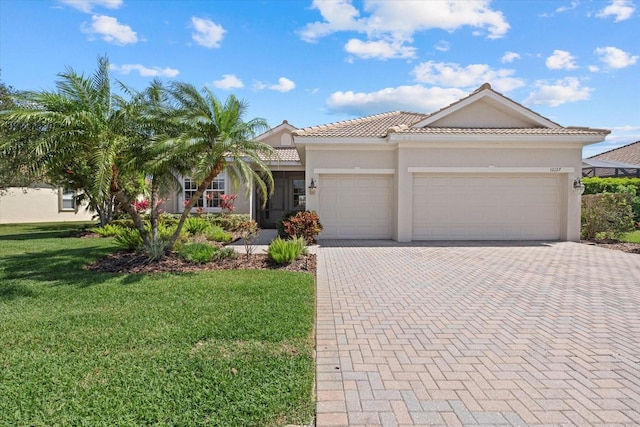 view of front of home featuring a tiled roof, a front yard, stucco siding, decorative driveway, and an attached garage