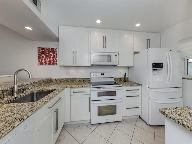 kitchen featuring light stone counters, light tile patterned flooring, white cabinets, white appliances, and a sink