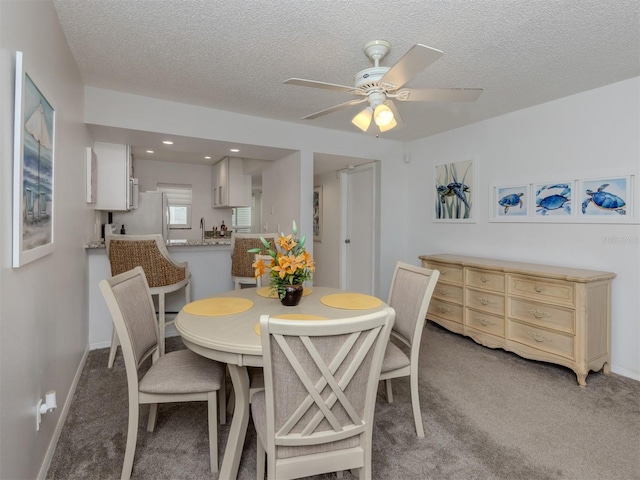 dining area featuring a textured ceiling, recessed lighting, baseboards, light colored carpet, and ceiling fan