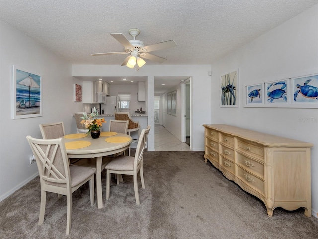 dining room with a textured ceiling, ceiling fan, light tile patterned floors, and light carpet