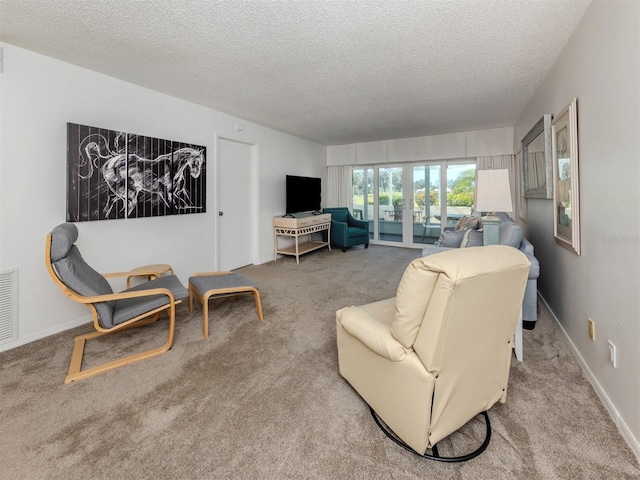 carpeted living room featuring baseboards, visible vents, and a textured ceiling