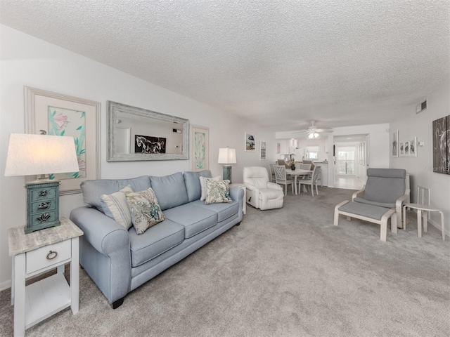 carpeted living area featuring visible vents, a textured ceiling, and a ceiling fan