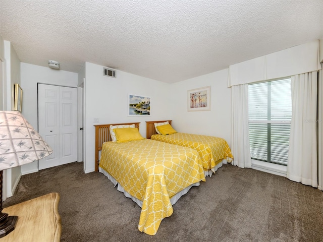 bedroom with carpet, visible vents, and a textured ceiling