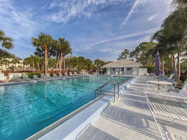 pool with a patio, fence, and an outdoor structure