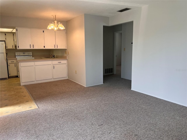 kitchen featuring light colored carpet, visible vents, freestanding refrigerator, and a sink