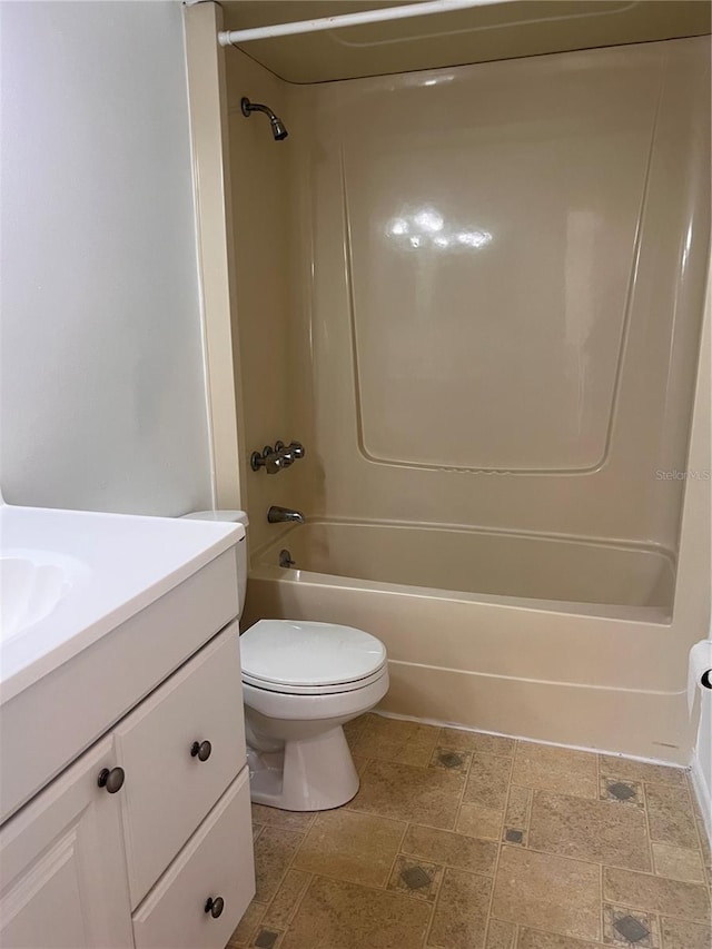 bathroom with toilet, tub / shower combination, vanity, and stone finish flooring