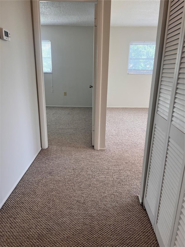 corridor with a textured ceiling and carpet floors