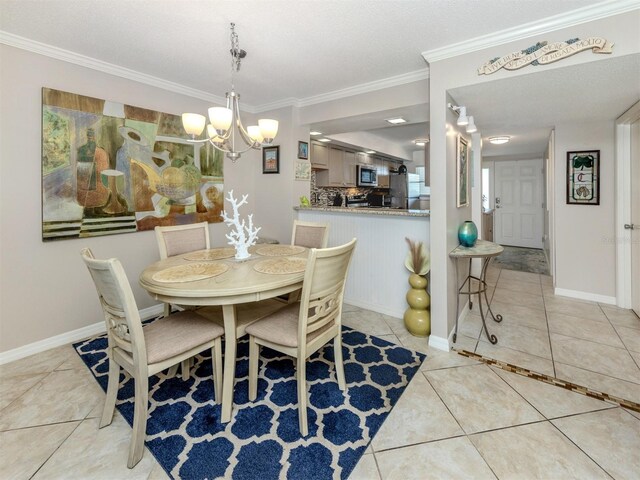 dining area with an inviting chandelier, light tile patterned floors, baseboards, and ornamental molding